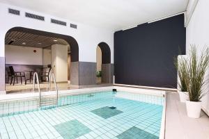 a swimming pool with a tile floor and a large screen at Scandic Swania in Trollhättan