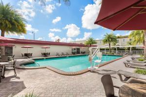 einen Pool in einem Hotel mit Tischen und Stühlen in der Unterkunft Ramada by Wyndham Miami Springs/Miami International Airport in Miami