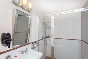 a white bathroom with a shower and a sink at Ramada by Wyndham Miami Springs/Miami International Airport in Miami