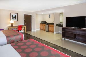 a hotel room with a bed and a flat screen tv at Ramada by Wyndham Miami Springs/Miami International Airport in Miami