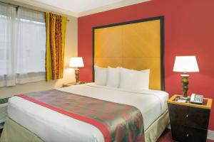 a hotel room with a large bed and red walls at Ramada by Wyndham Miami Springs/Miami International Airport in Miami