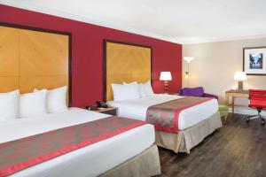 a hotel room with two beds and a desk at Ramada by Wyndham Miami Springs/Miami International Airport in Miami