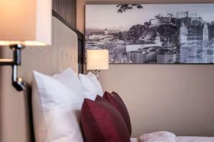 a bed with pillows and a picture on the wall at Wyndham Grand Salzburg Conference Centre in Salzburg