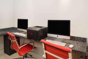 a desk with two computer monitors and a printer at Ramada by Wyndham Miami Springs/Miami International Airport in Miami