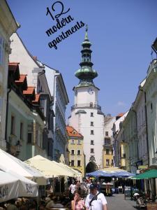 een stadsstraat met een klokkentoren op de achtergrond bij Aapartamentoos in Bratislava