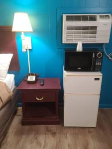 um quarto com uma cama e um ar condicionado e uma mesa com um candeeiro em Etown Motel em Elizabethtown