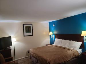 une chambre d'hôtel avec un lit doté d'une tête de lit bleue dans l'établissement Etown Motel, à Elizabethtown