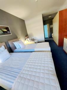 two large beds in a hotel room with a man laying on a bed at Hotel Villa Valpovo in Valpovo