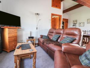 a living room with a brown leather couch and a tv at Granary in Clitheroe