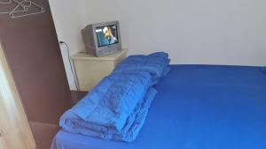 a bed with a blue sleeping bag next to a tv at Camping Aviator Busteni, camere in Buşteni