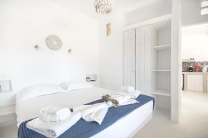 a white bedroom with a bed with towels on it at Andria's suites in Chrissi Akti