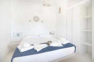 a white bedroom with a bed with towels on it at Andria's suites in Chrissi Akti