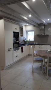 a kitchen with white cabinets and a wooden table at Appartement Béthanie in Steige