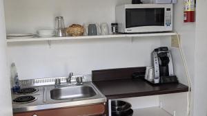 eine kleine Küche mit einer Spüle und einer Mikrowelle in der Unterkunft Valois Motel & Restaurant in Mattawa