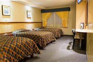 a hotel room with three beds with yellow curtains at Los Mirtos suite & Hotel in Lima