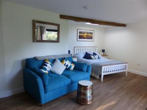 a living room with a blue couch and a bed at Conkers - a new bespoke rural escape near Glastonbury in Glastonbury