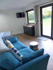 a living room with a blue couch and a television at Conkers - a new bespoke rural escape near Glastonbury in Glastonbury
