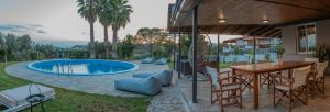 a patio with a table and chairs and a swimming pool at Cuervo Poolside Villa in Kalívia Thorikoú