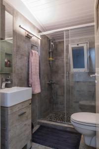 a bathroom with a shower and a sink and a toilet at Cuervo Poolside Villa in Kalívia Thorikoú