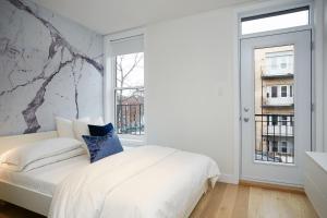a bedroom with a white bed and a window at Explore Montreal from Sleek Contemporary Apartment by Den Stays in Montreal