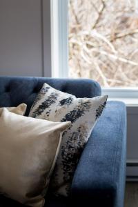a blue couch with pillows sitting in front of a window at Stunning 1 Bedroom in Mile End by Den Stays in Montréal