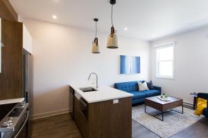 a kitchen and a living room with a blue couch at Perfectly Located Mile End 2 Bdr Unit by Den Stays in Montréal