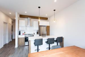une cuisine avec des placards blancs et un îlot de cuisine avec des chaises dans l'établissement Light Filled 2 Bdr Unit in Mile End by Den Stays, à Montréal
