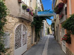 an alley in an old town with a sign on a building at chez le tit in Mèze