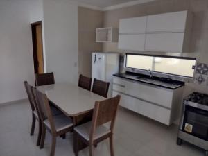 a kitchen with a table and chairs and a refrigerator at Residencial Secret Point in Praia do Frances