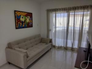 a living room with a couch and a painting on the wall at Residencial Secret Point in Praia do Frances