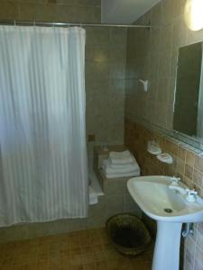 a bathroom with a shower curtain a sink and a toilet at Hostería Restaurante del Puerto in Colón