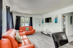 a living room with an orange couch and a chair at Tropical Getaway/ Stunning 2BR Gem in West Palm Beach