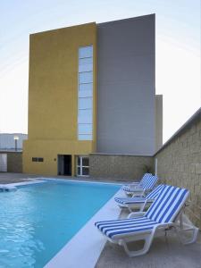 uma piscina com espreguiçadeiras ao lado de um edifício em City Express by Marriott Salina Cruz em Salina Cruz