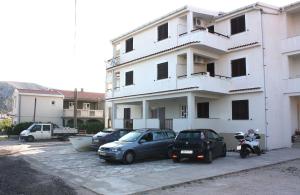 two cars parked in a parking lot in front of a building at Batkoski Apartments in Pag