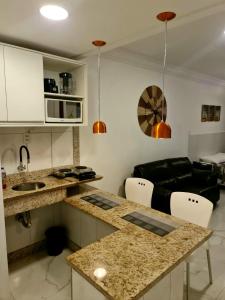 cocina y sala de estar con sofá negro en Flat Na Barra, en Salvador