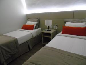 a hotel room with two beds with orange pillows at Samba Tres Rios in Três Rios
