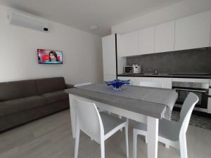 cocina con mesa, sillas y sofá en Jesolo Appartamenti F2 - Ocean Blue, en Lido di Jesolo