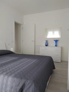 リド・ディ・イエゾロにあるJesolo Appartamenti F2 - Ocean Blueのベッドルーム1室(ベッド1台、青い花瓶2本付)