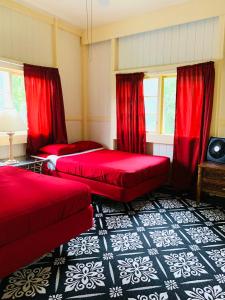 a bedroom with two beds and red curtains at Wild Ginger Hotel in Hilo