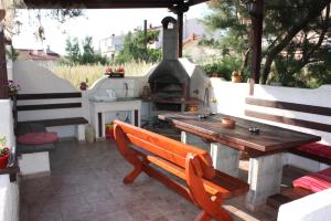 un patio con una mesa de madera y un horno de pizza en Batkoski Apartments, en Pag