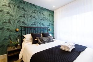1 dormitorio con 1 cama con una pared verde arbolada en Golden Oasis Studio with Yard View and full bath by Den Stays, en Montreal