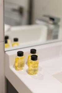 three bottles of oil sitting on a bathroom counter at Studio Palms Steps from JeanTalon Market Full Bath by Den Stays in Montréal +71 photos