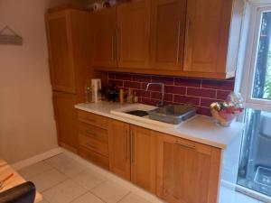 uma cozinha com armários de madeira e um lavatório em 3 bed corner terrace house by the sea Wicklow town em Wicklow