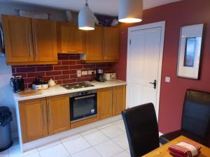 La cuisine est équipée de placards en bois et d'un four avec plaques de cuisson. dans l'établissement 3 bed corner terrace house by the sea Wicklow town, à Wicklow