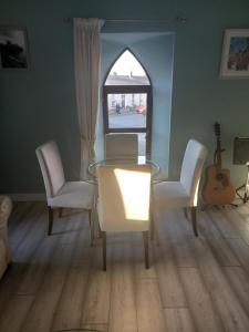 a dining room with a glass table and white chairs at 3 bed corner terrace house by the sea Wicklow town in Wicklow