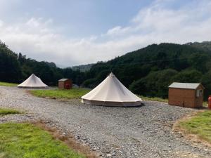 duas tendas ao lado de uma estrada de cascalho em Dyfi Dens Machynlleth em Esgair-geiliog