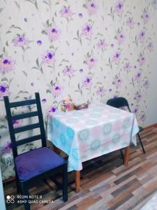 a table and two chairs and a wall with purple flowers at Апартаменты на Пушкина, 13 in Perm