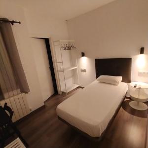Un dormitorio con una gran cama blanca y una mesa en Room Pride, en Madrid