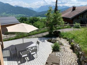 eine Terrasse mit einem Sonnenschirm, einem Tisch und Stühlen in der Unterkunft Bregenzerwaldblick in Schwarzenberg im Bregenzerwald