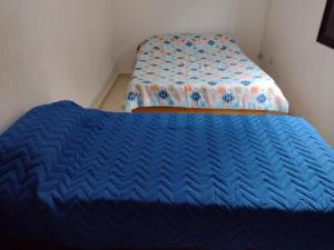 1 cama con edredón azul en una habitación en Balneário Maracanã - Praia Grande - Aceita Pet - 50 mts praia, en Praia Grande